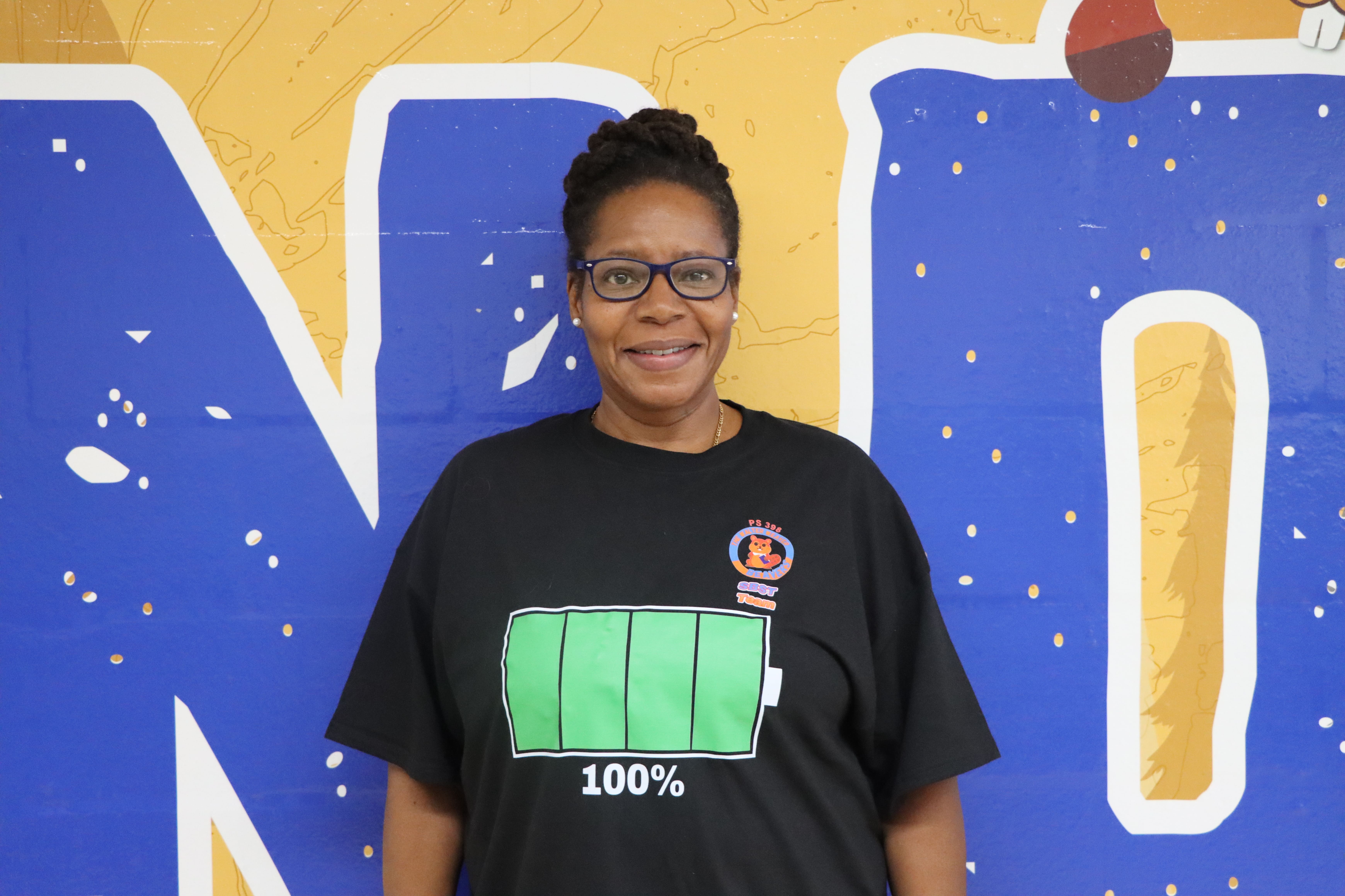 Staff member smiling in front of colorful school mural