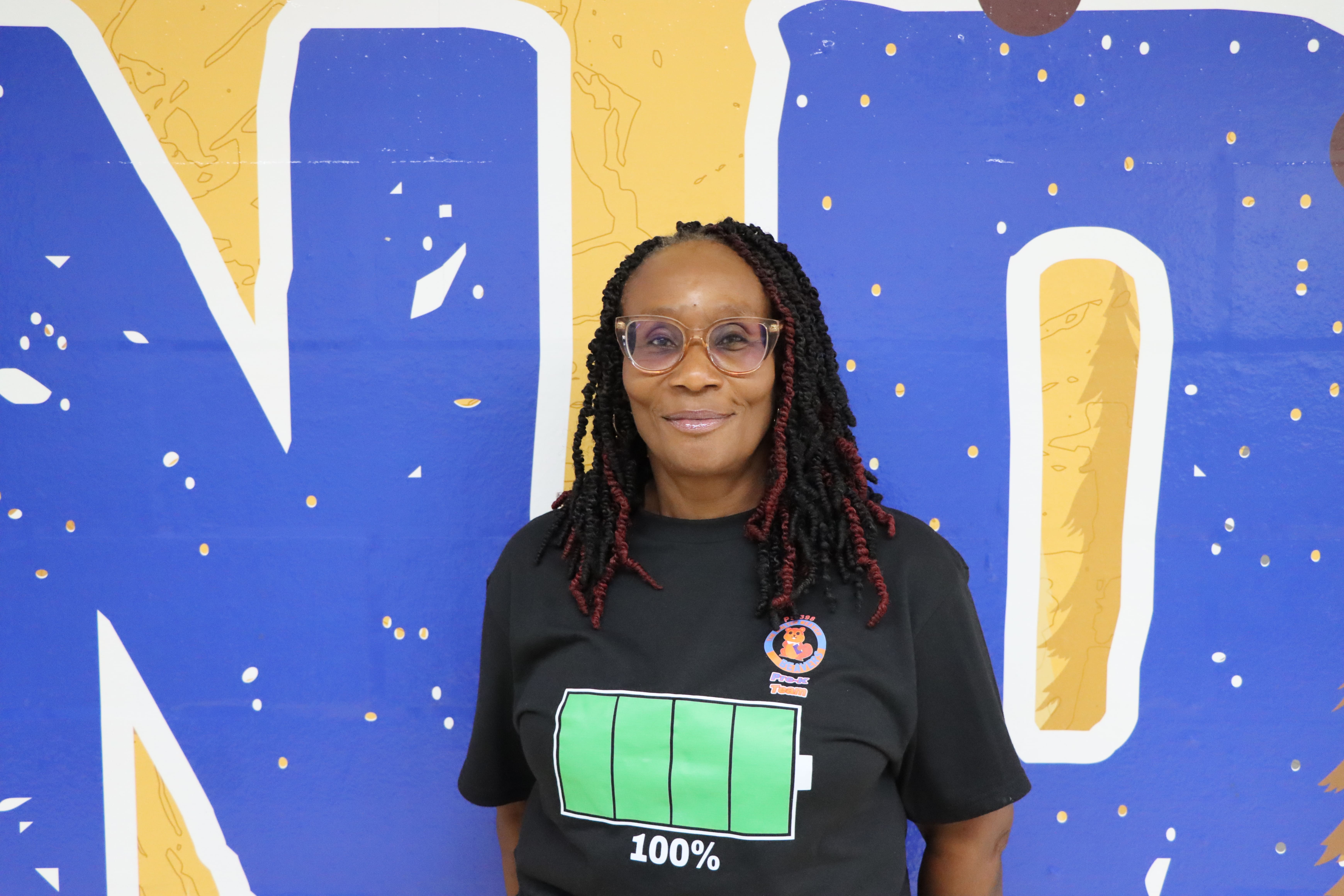 Staff member wearing battery t-shirt against blue mural