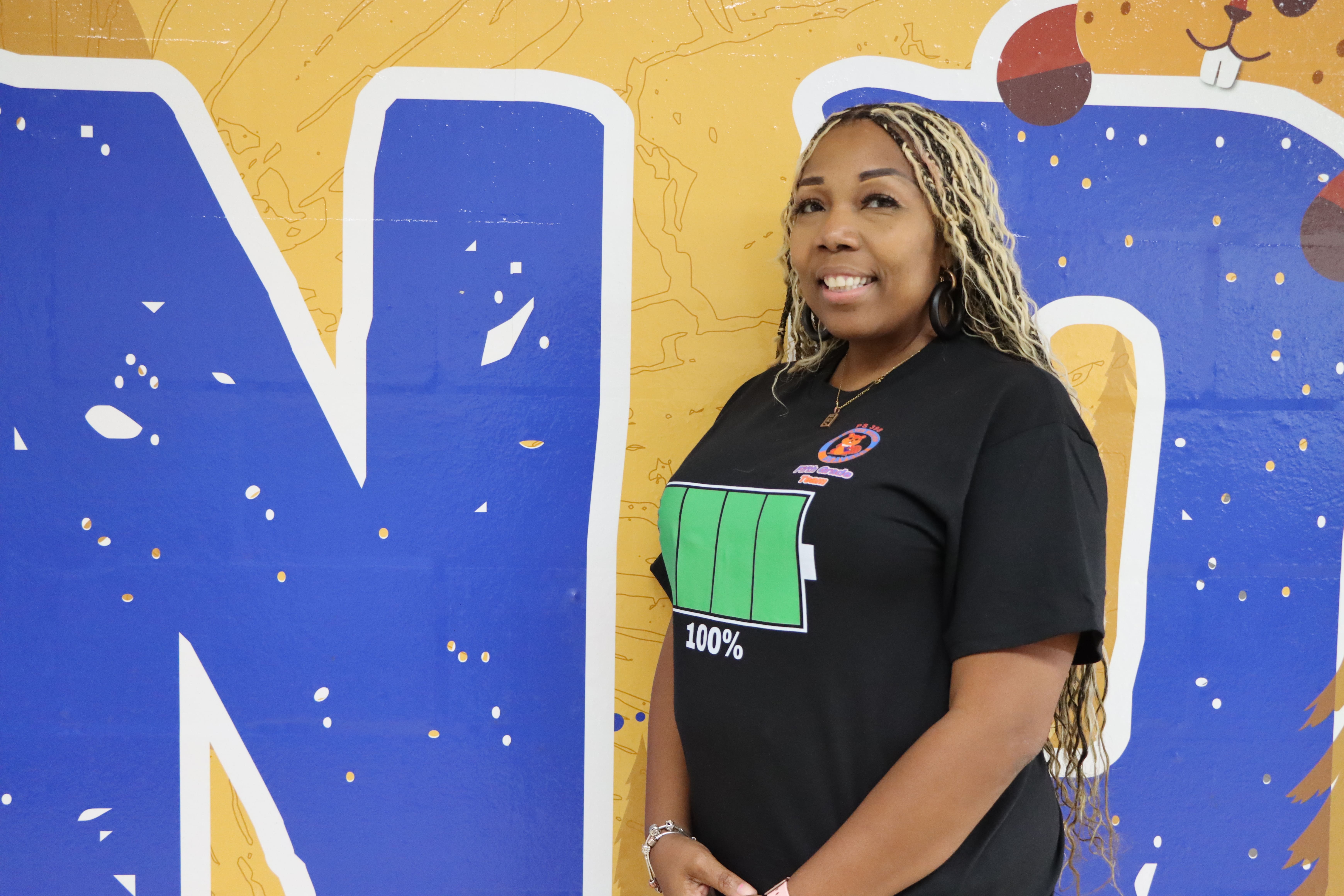 Staff member posing in front of colorful school mural