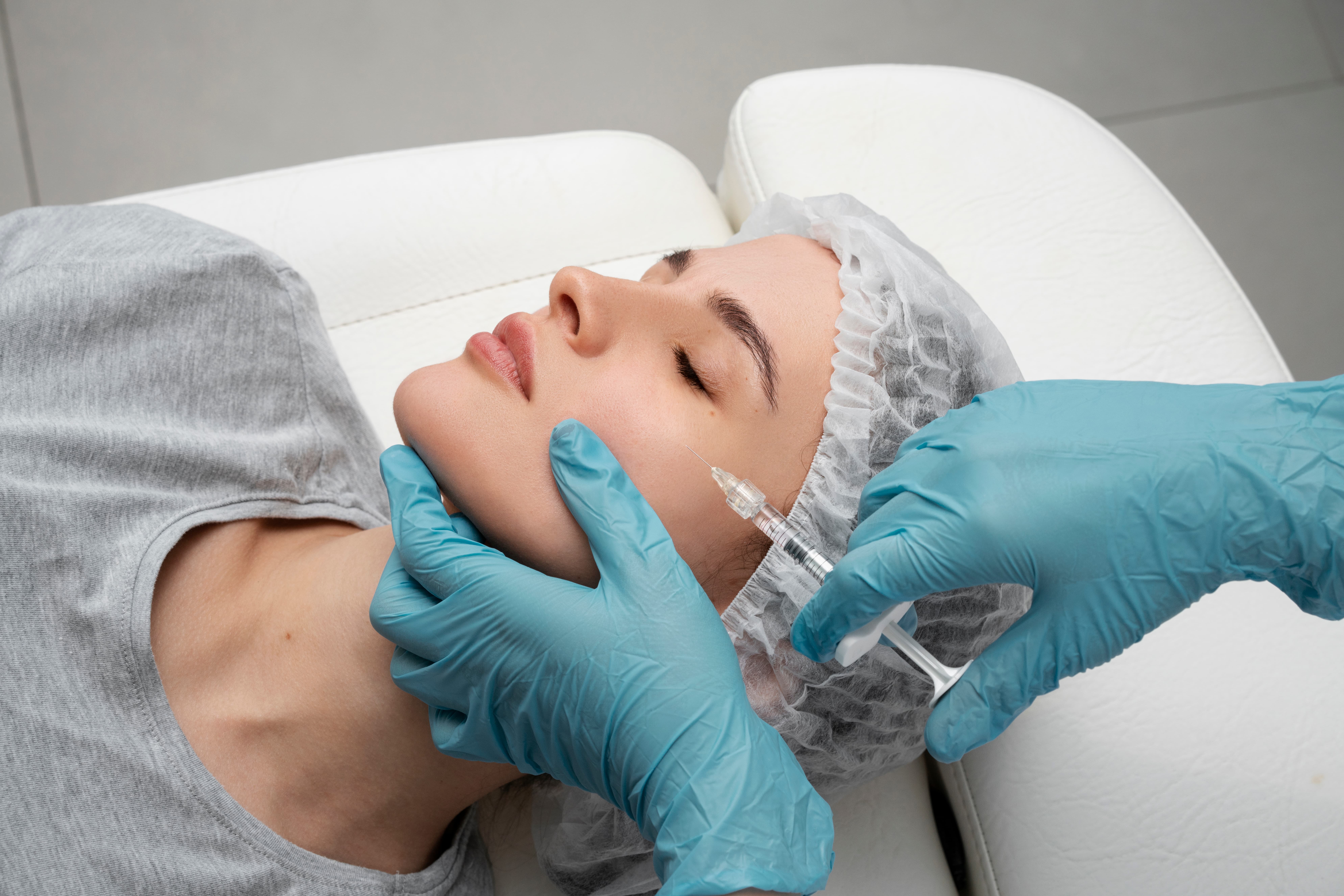 Woman receiving a skin booster microneedling treatment on her face at a skin clinic.