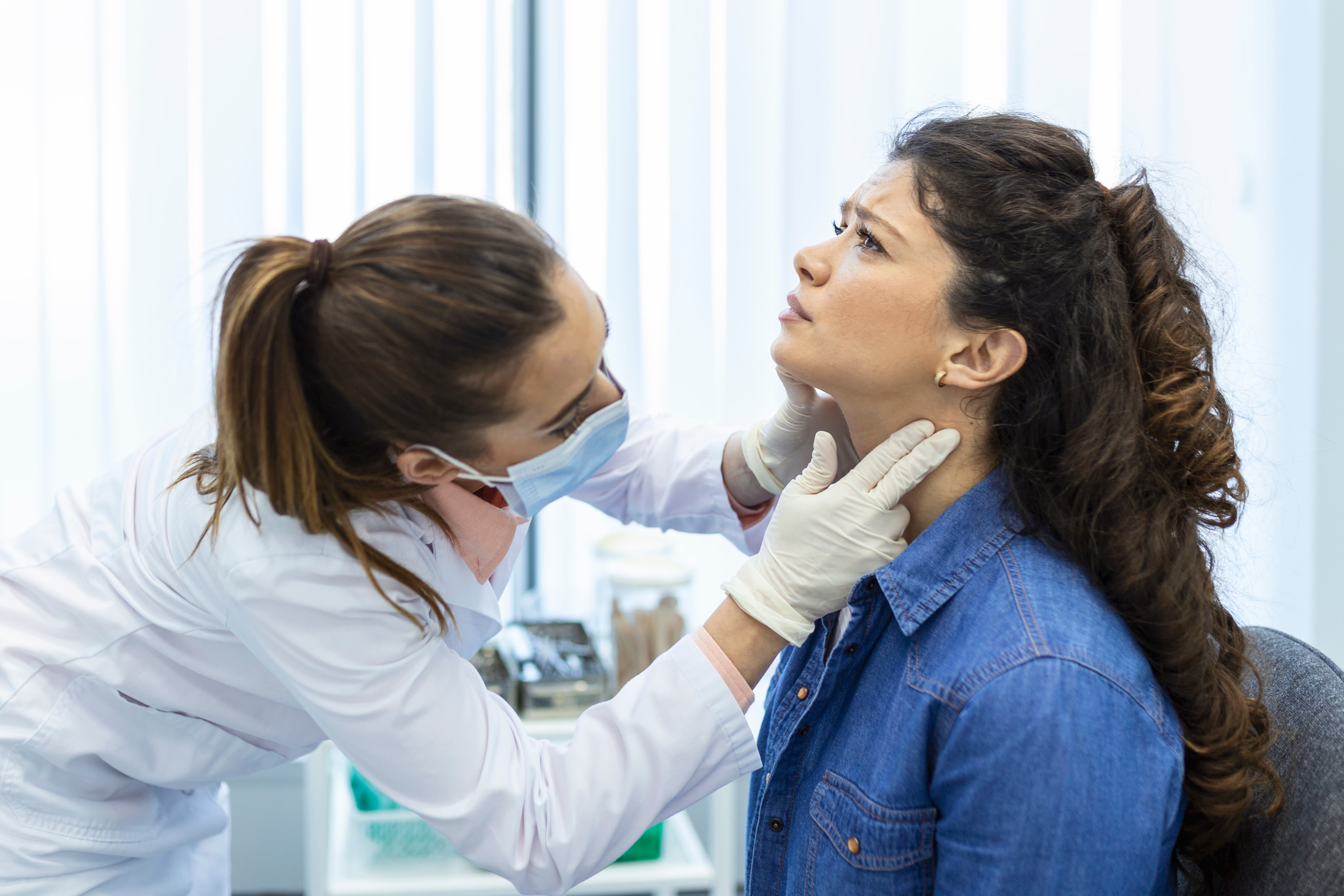  Doctor examining a patient's chin and neck during a double chin surgery consultation.