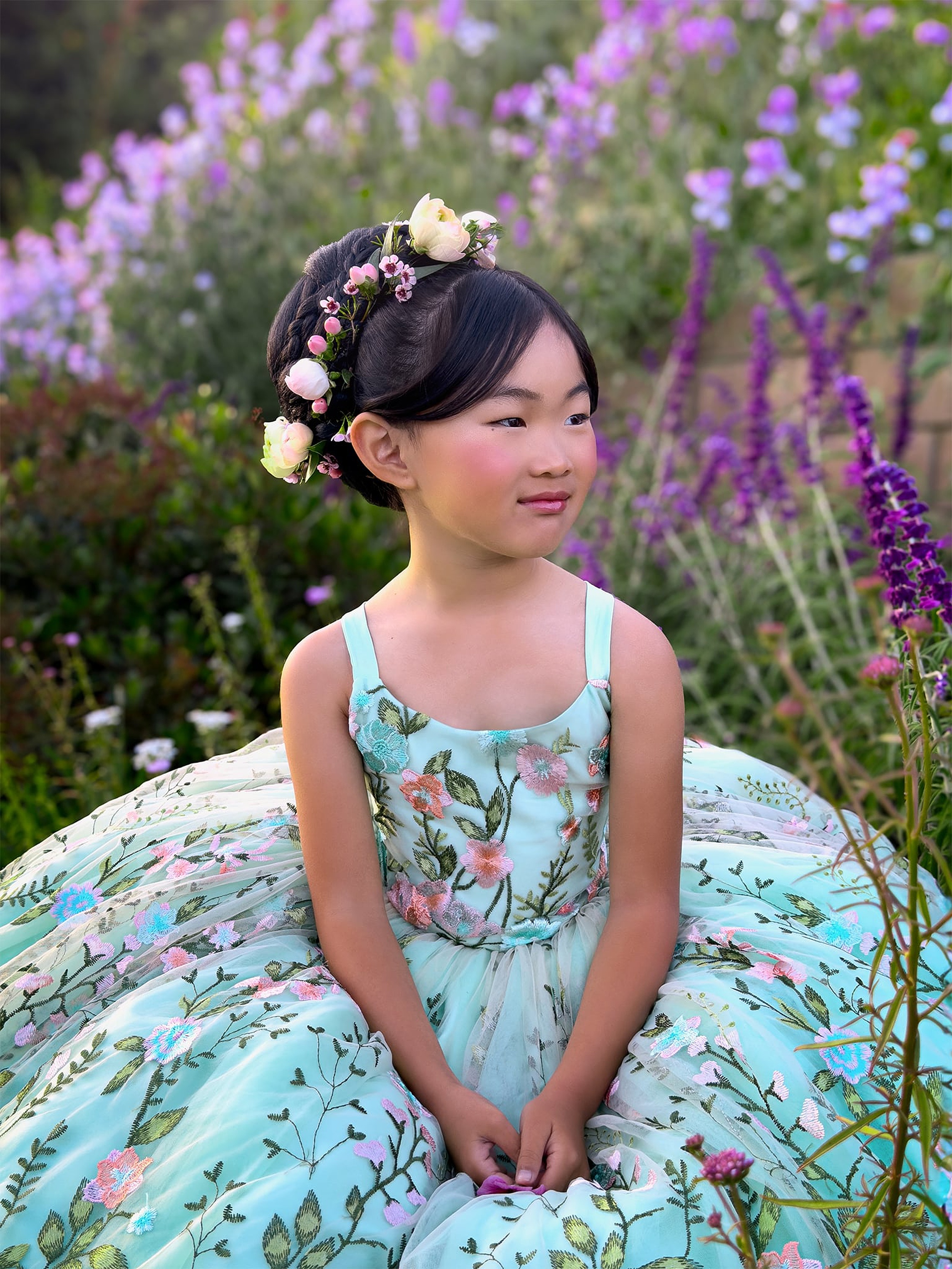 A young girl in a blue princess dress sits in a field of purple flowers thanks to iPhone Photography Tips