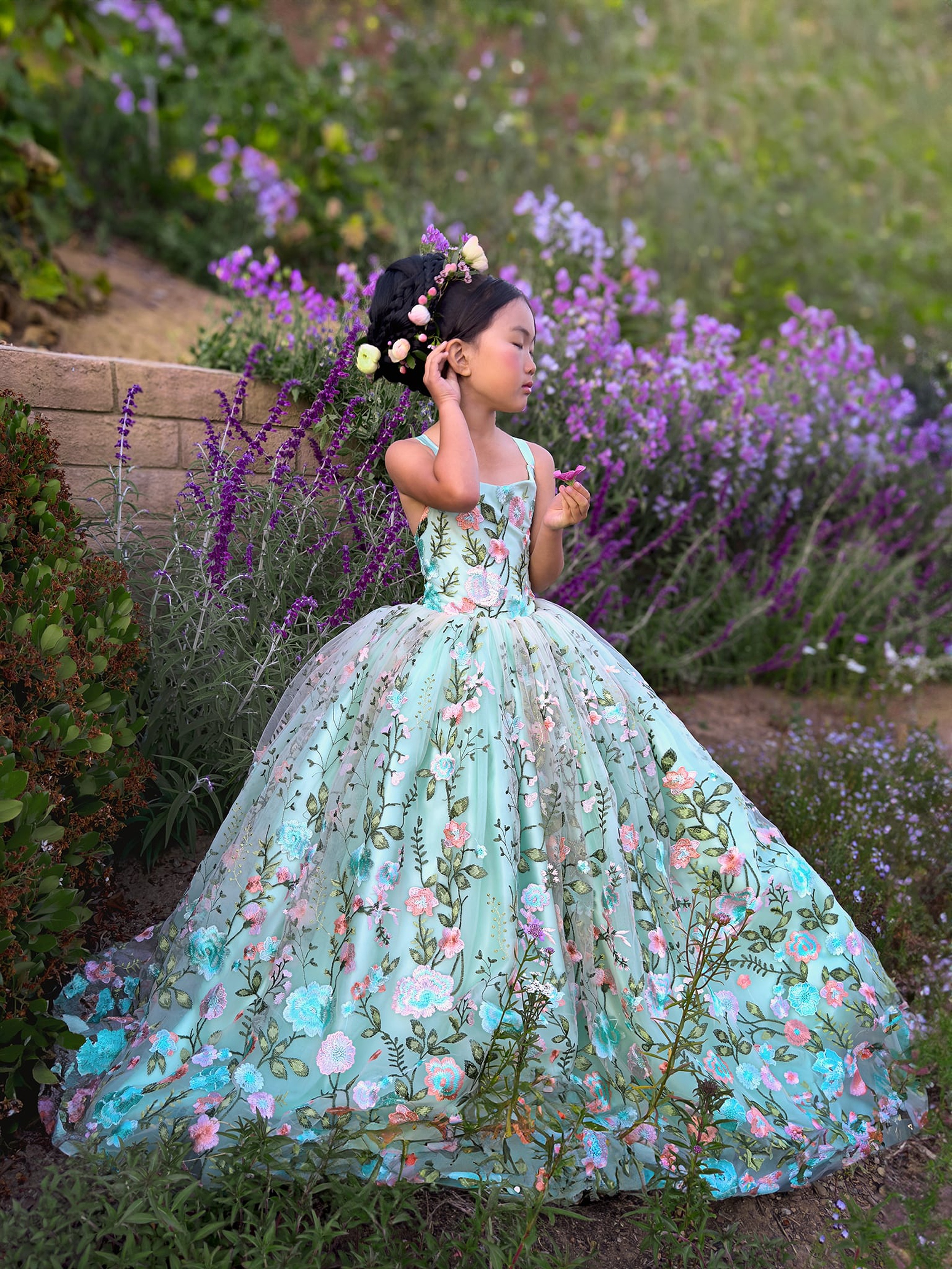 A young girl explores a garden while wearing a bright blue princess dress thanks to iPhone Photography Tips