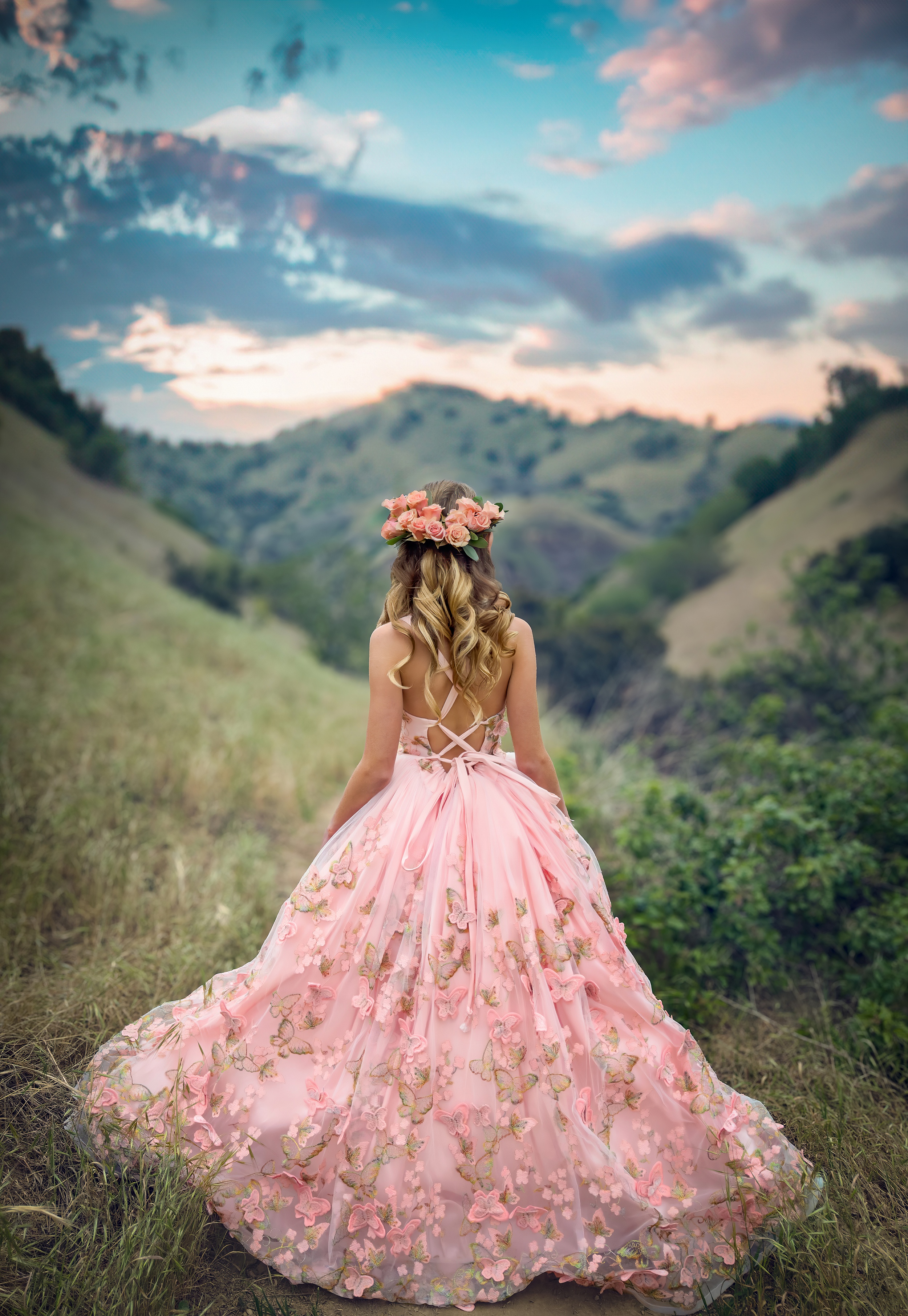 A RAW iPhone Photo of a young girl in a flowing pink princess gown in the mountains