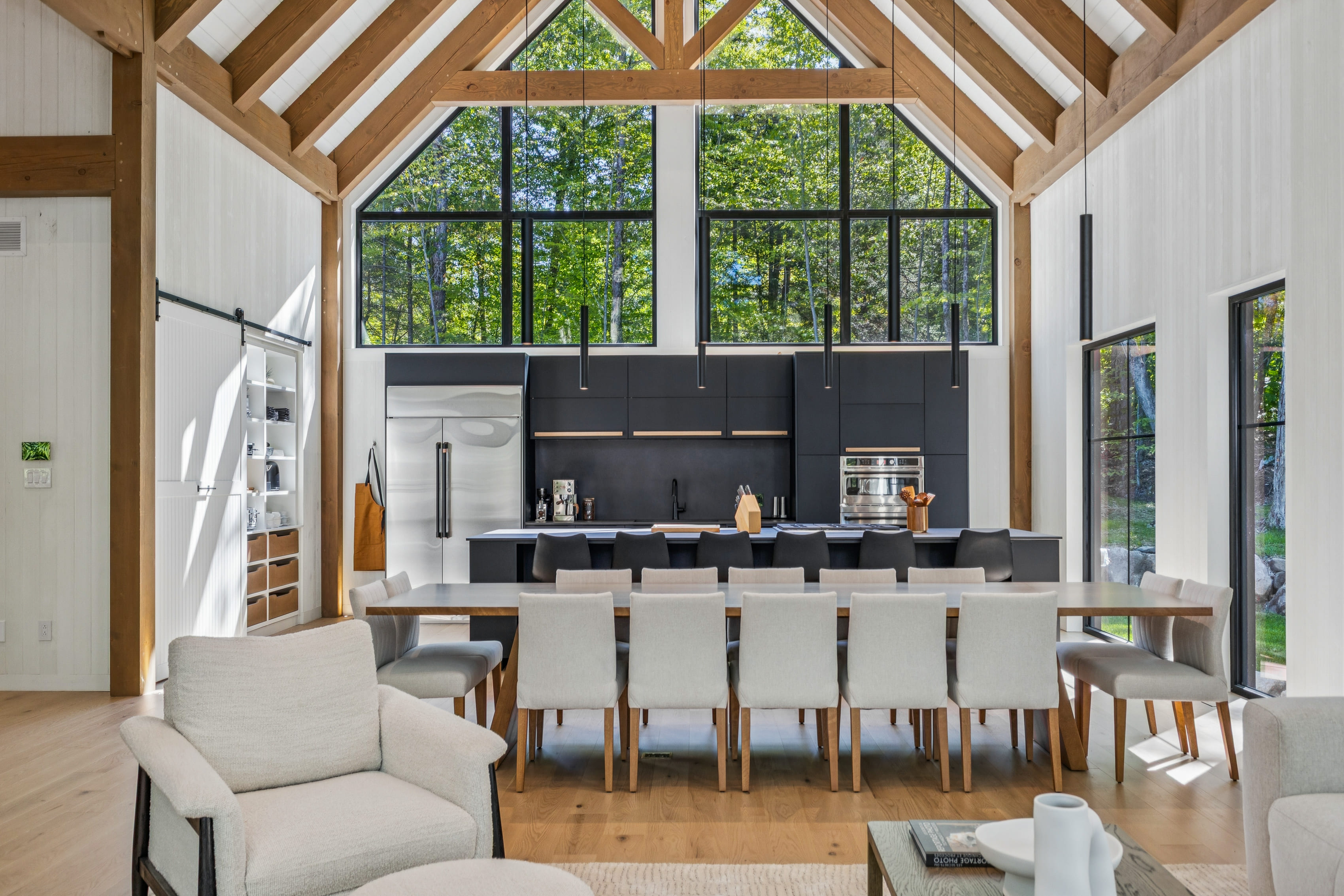 Architectural photography by Parsell of a luxury great room with a vaulted, timber-frame ceiling and open-concept kitchen, for marketing high-end properties in the Outaouais and Laurentians. | Photographie architecturale par Parsell d'une aire ouverte de luxe avec un plafond cathédrale à charpente de bois et cuisine ouverte, pour le marketing de propriétés haut de gamme en Outaouais et dans les Laurentides.