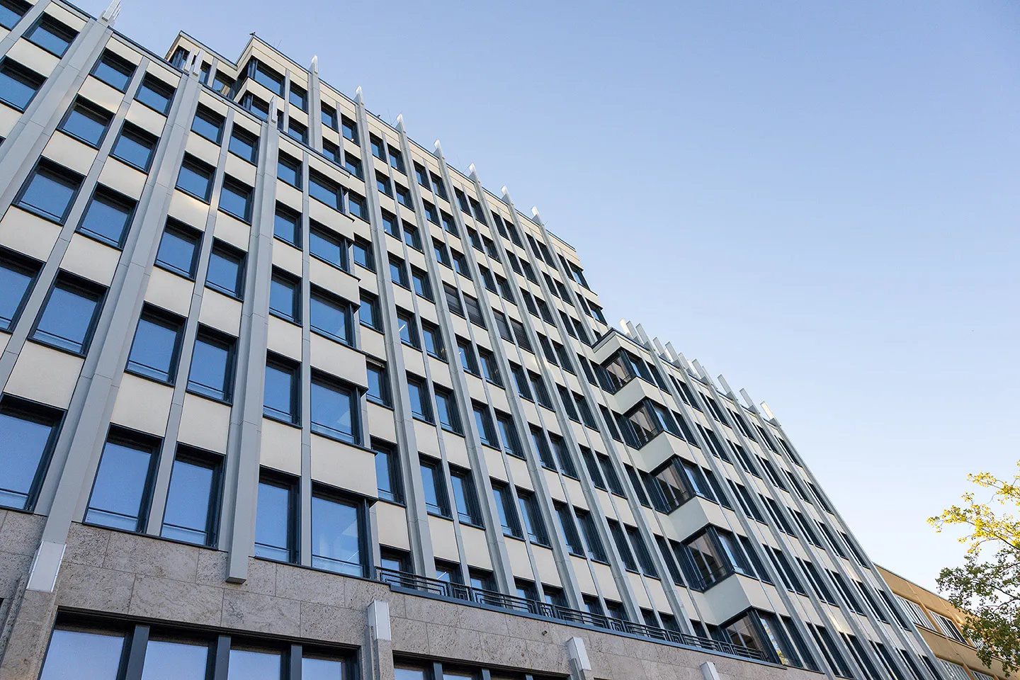 Moderner Bürogebäudefassade mit vielen Fenstern unter klarem Himmel.