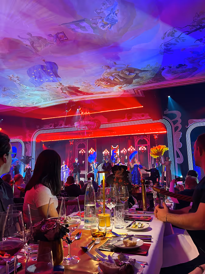 Audience seated at a dinner event watching a colorful stage performance.