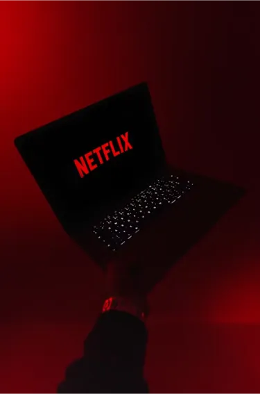 Netflix on a laptop, red background. AI agents and entertainment.