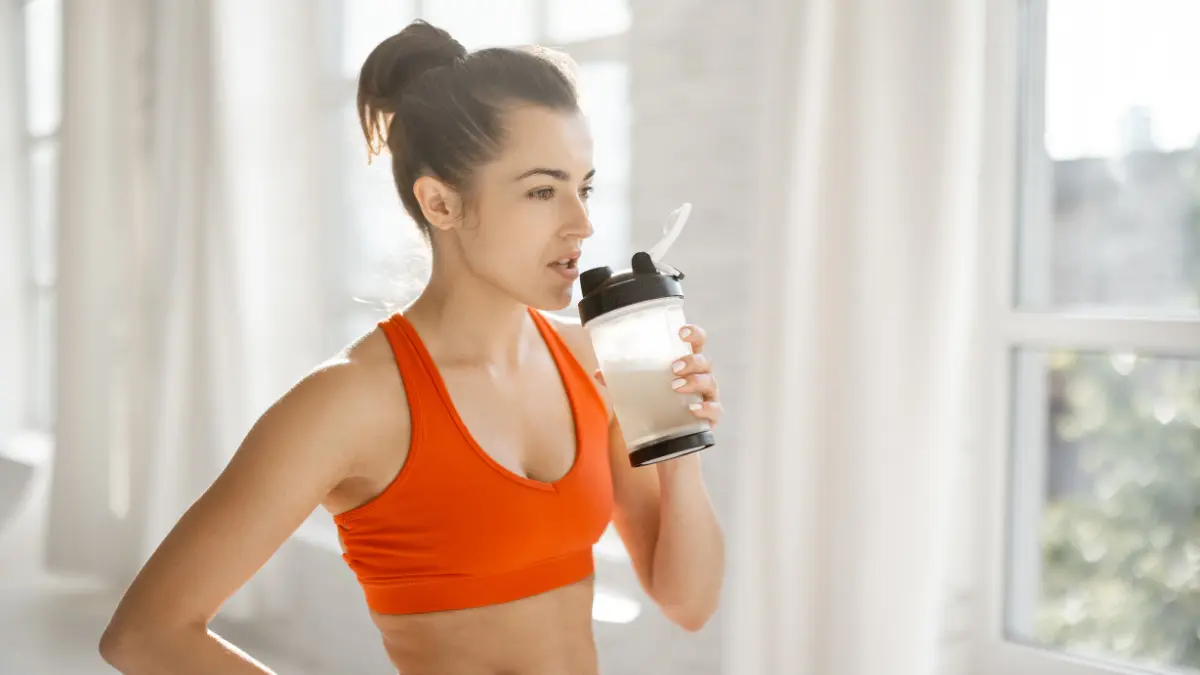 Žena nakon treninga pije proteinski shake za debljanje