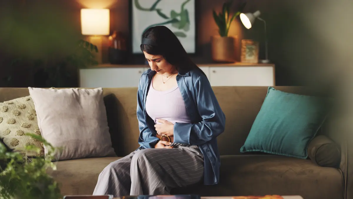 a woman holding the abdominal area because of lower belly bloating