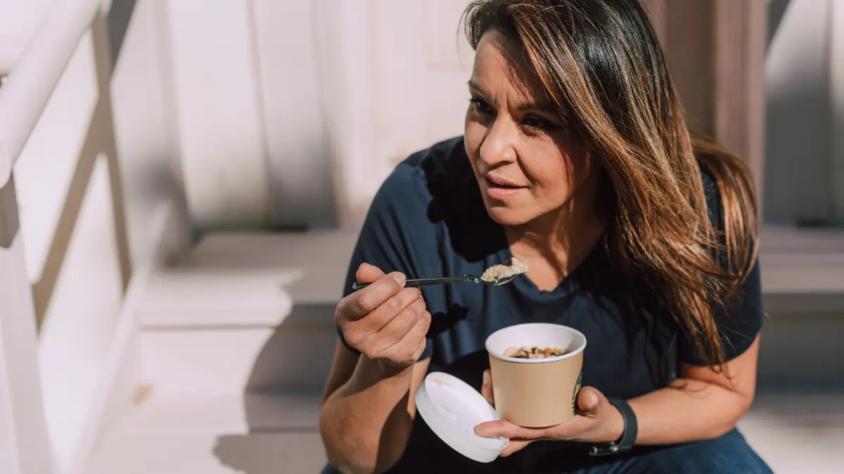 Žena na pauzi od posla jede zobene pahuljice za doručak