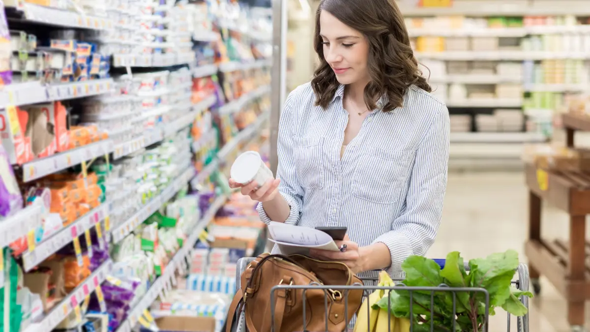 Žena u supermarketu bira zobene pahuljice gledajući deklaraciju na proizvodu