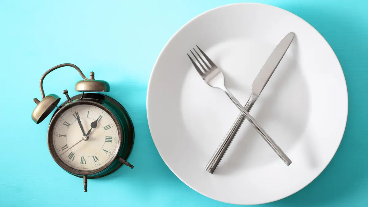 Tanjur s prekriženim escajgom i sat koji pokazuje intermittent fasting