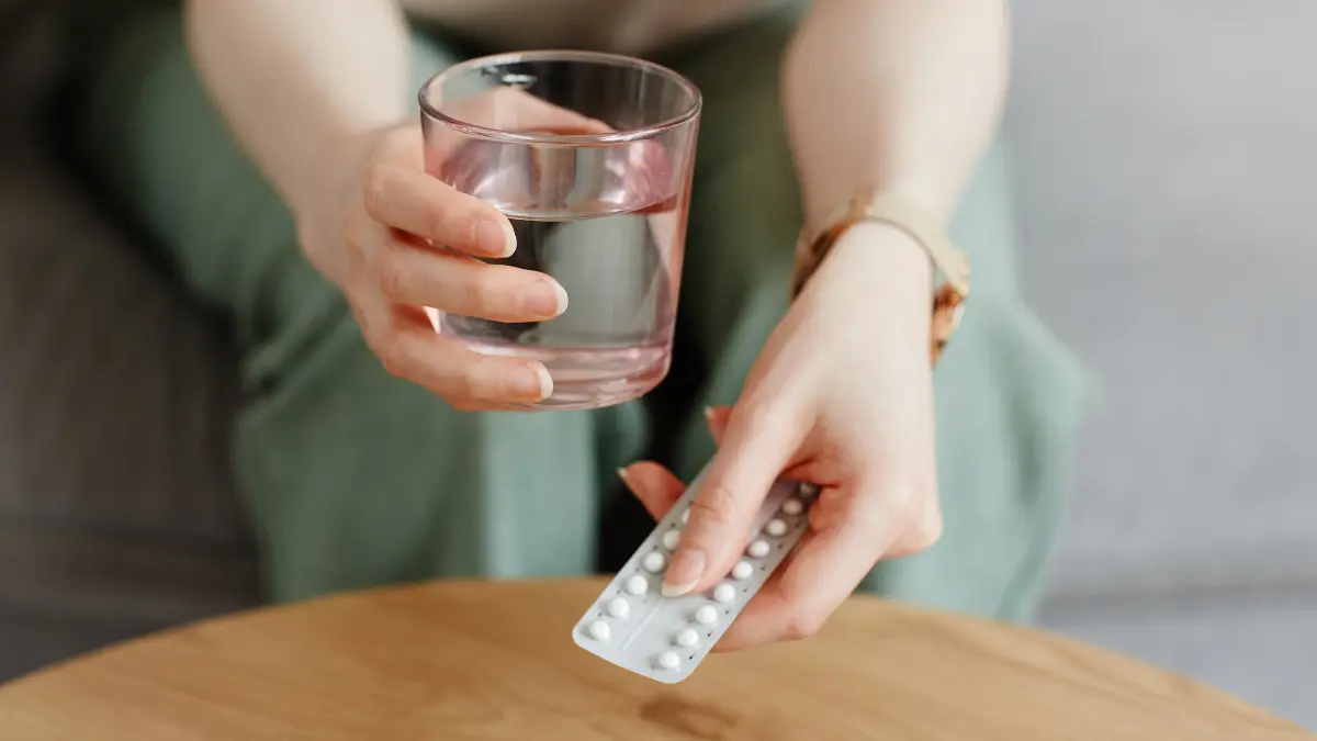 žena pije tablete glukozamina i kondroitina s čašom vode