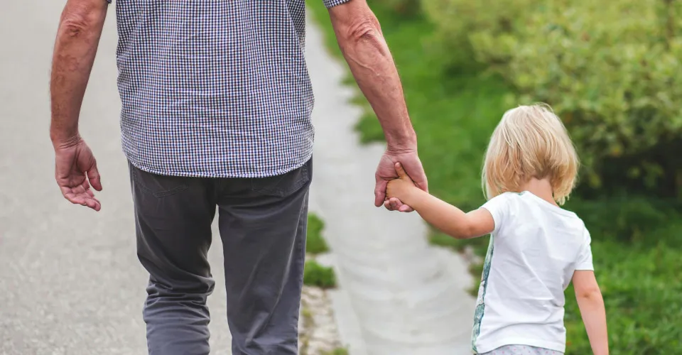 baby and adult holding hands on walk