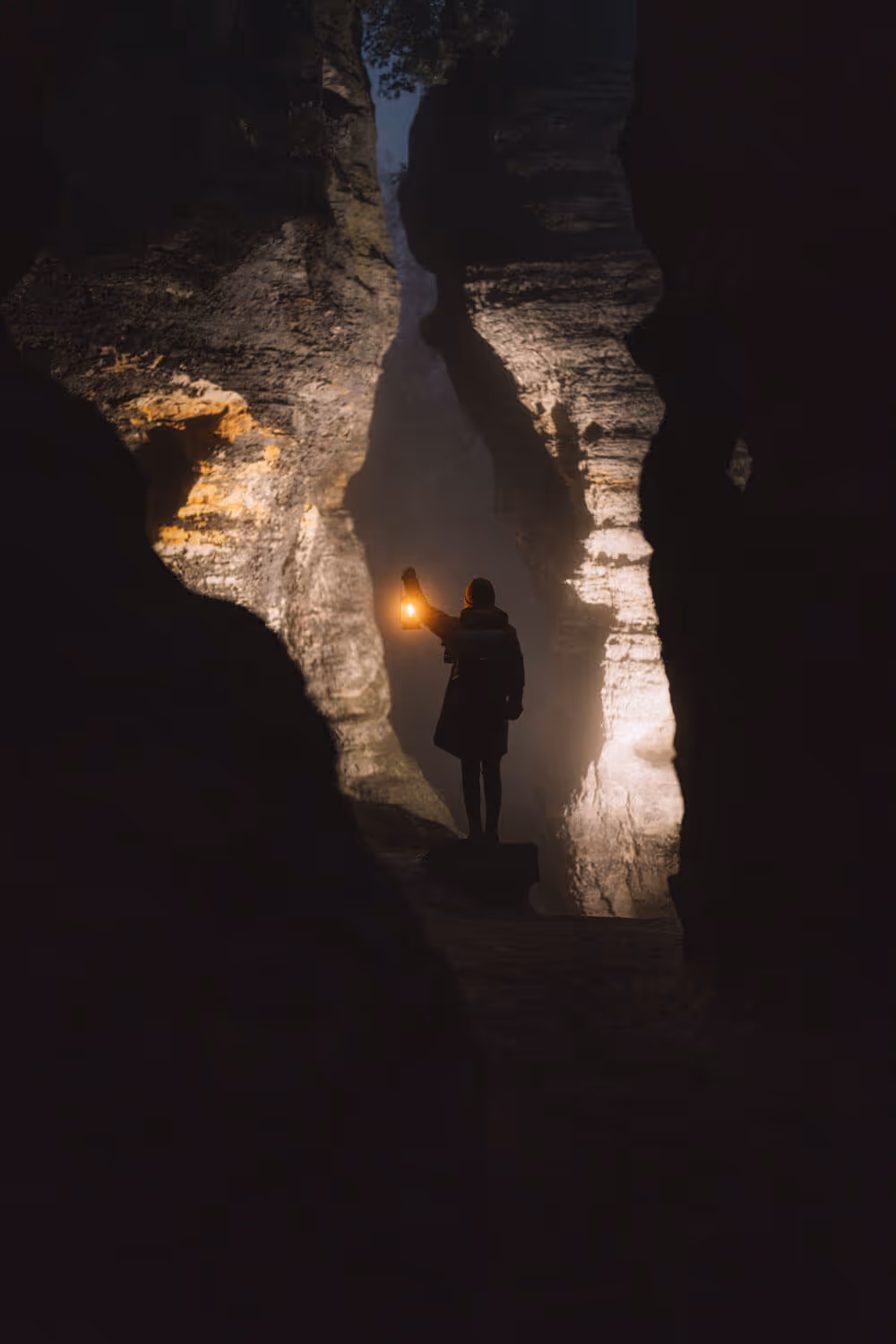 Silhouette with a lantern in a narrow sandstone gorge at night at Tisa Rocks.