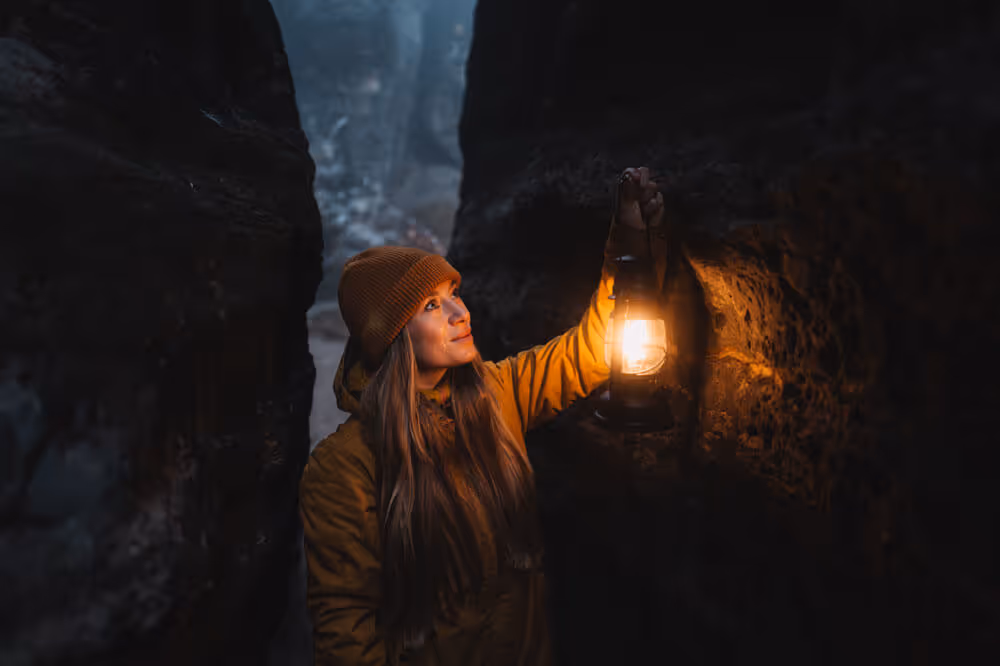 Guest holding a lantern in a narrow sandstone passage at night at Tisa Rocks, Bohemian Switzerland.