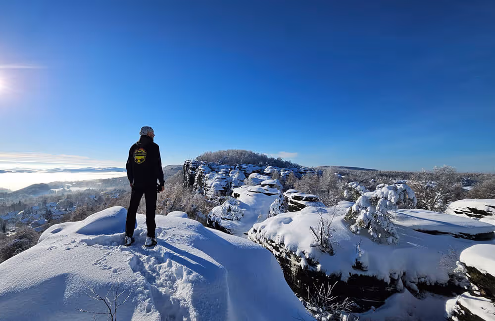 Guide on a snowy lookout above the sandstone cliffs of Tisa Rocks on a clear winter day in Bohemian Switzerland.