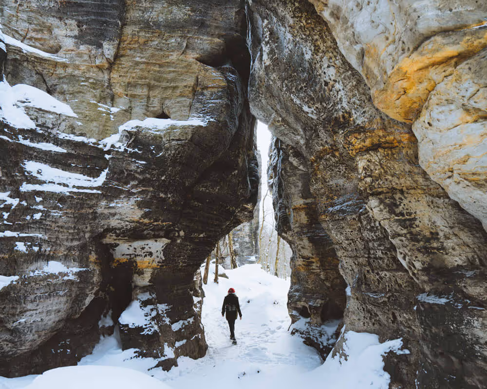 Guest walking through a snowy sandstone passage in Tisa Rocks on the Narnia & Bastei winter tour.