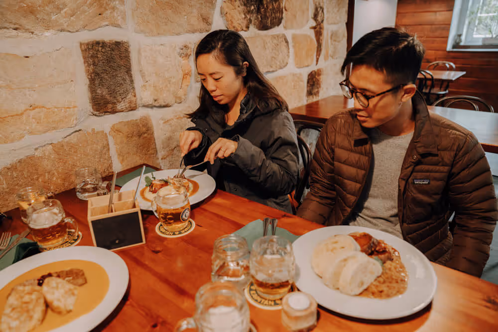 Two guests enjoying a traditional Czech meal with dumplings and beer during the Narnia & Bastei winter tour.