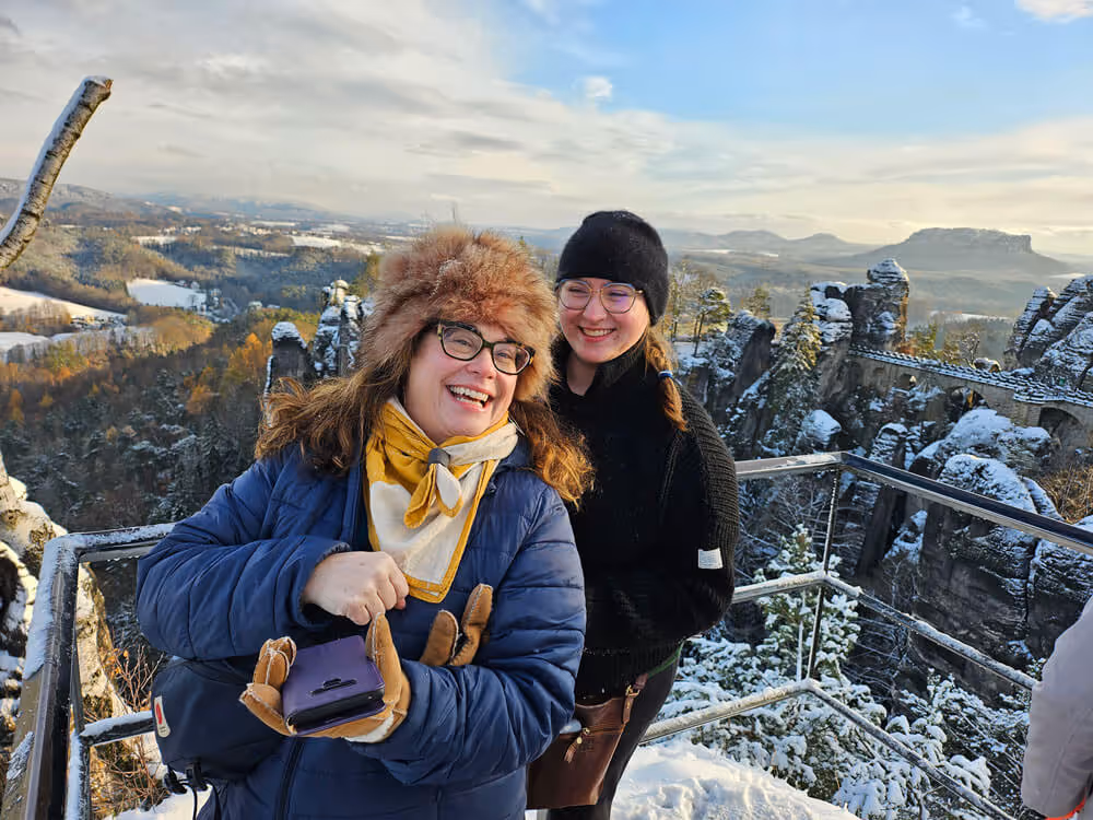 Smiling guests on the snowy Bastei viewpoint with sandstone cliffs in the background on the Narnia & Bastei tour.