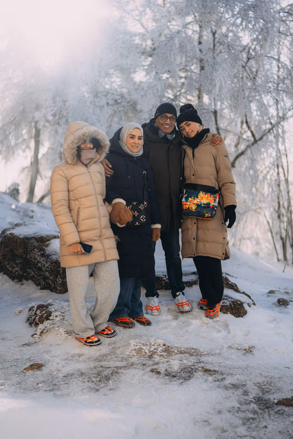 Group of four guests posing in winter coats and snow grips during the Narnia & Bastei winter tour.