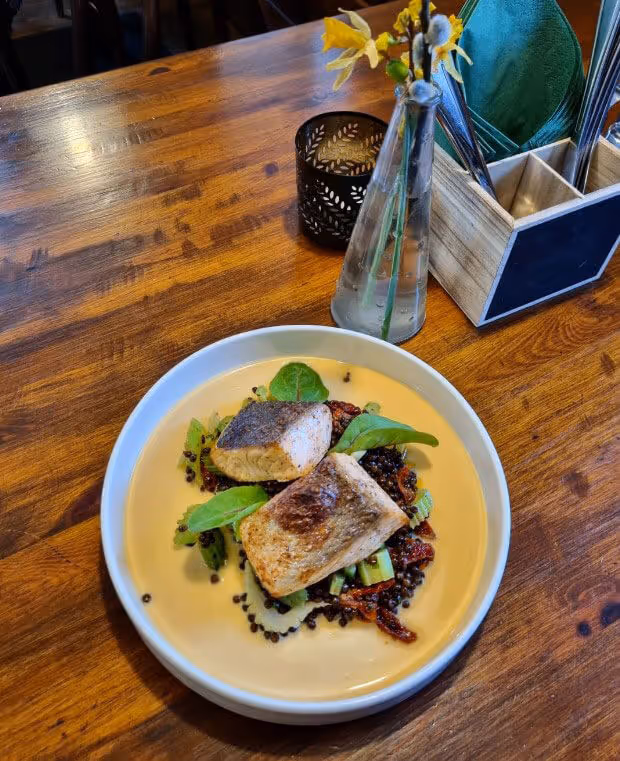 Pan-seared salmon with lentils and sun-dried tomatoes served at a cozy Czech countryside restaurant.