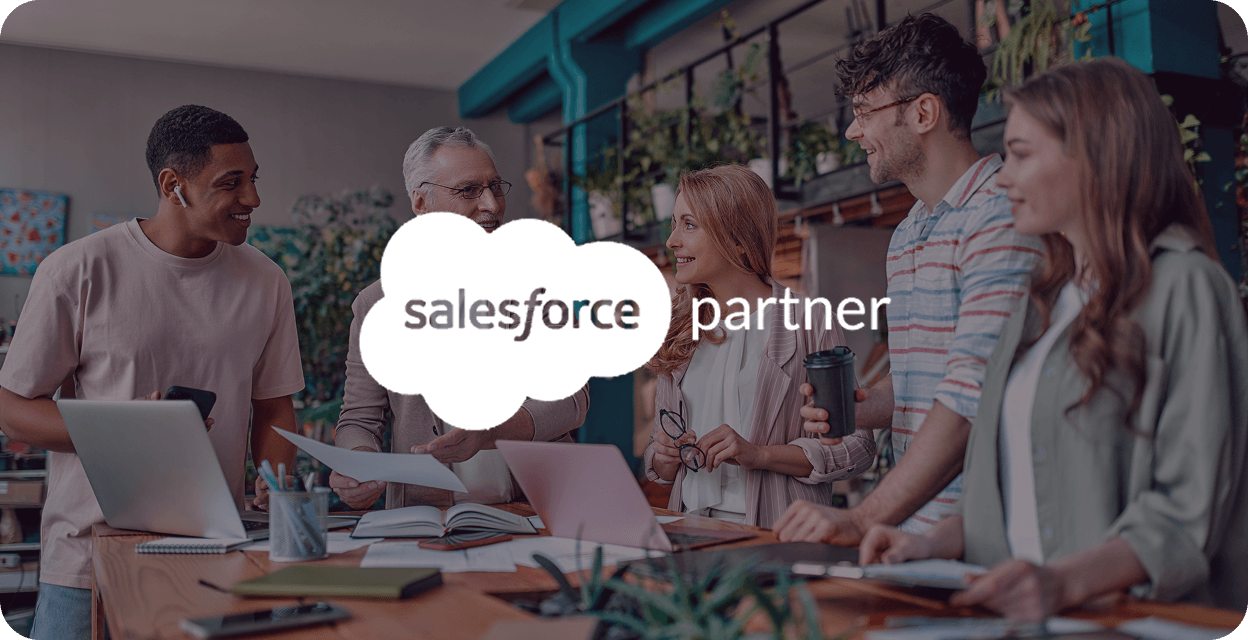 Group of five diverse colleagues smiling and collaborating around a table with laptops and papers in a modern office, overlaid with Salesforce partner logo.