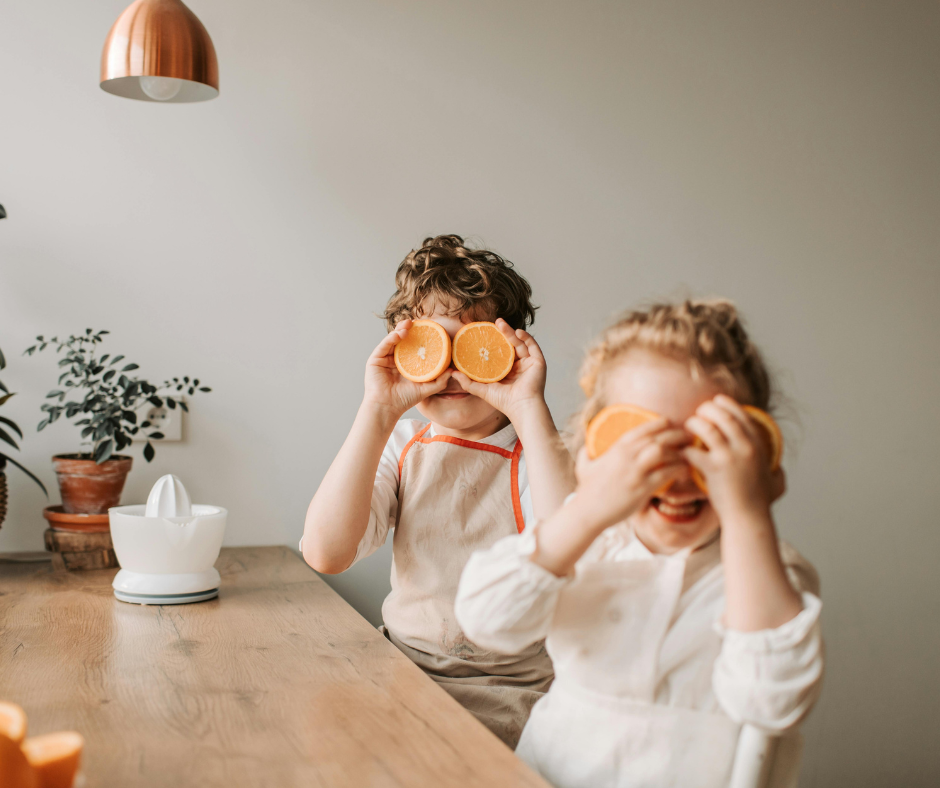 Two children cover their eyes with orange