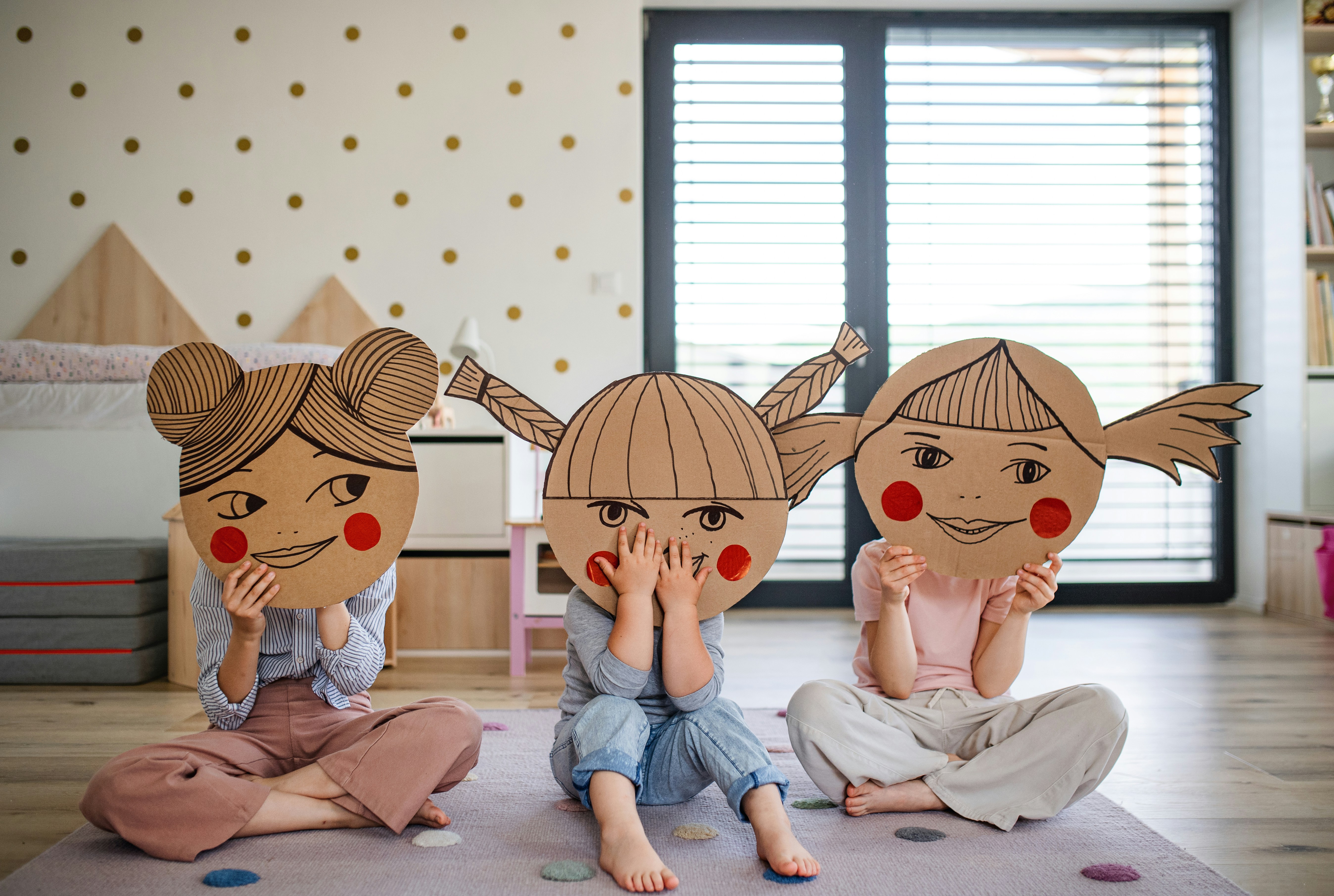 Three children using emotional cardboard cover their face