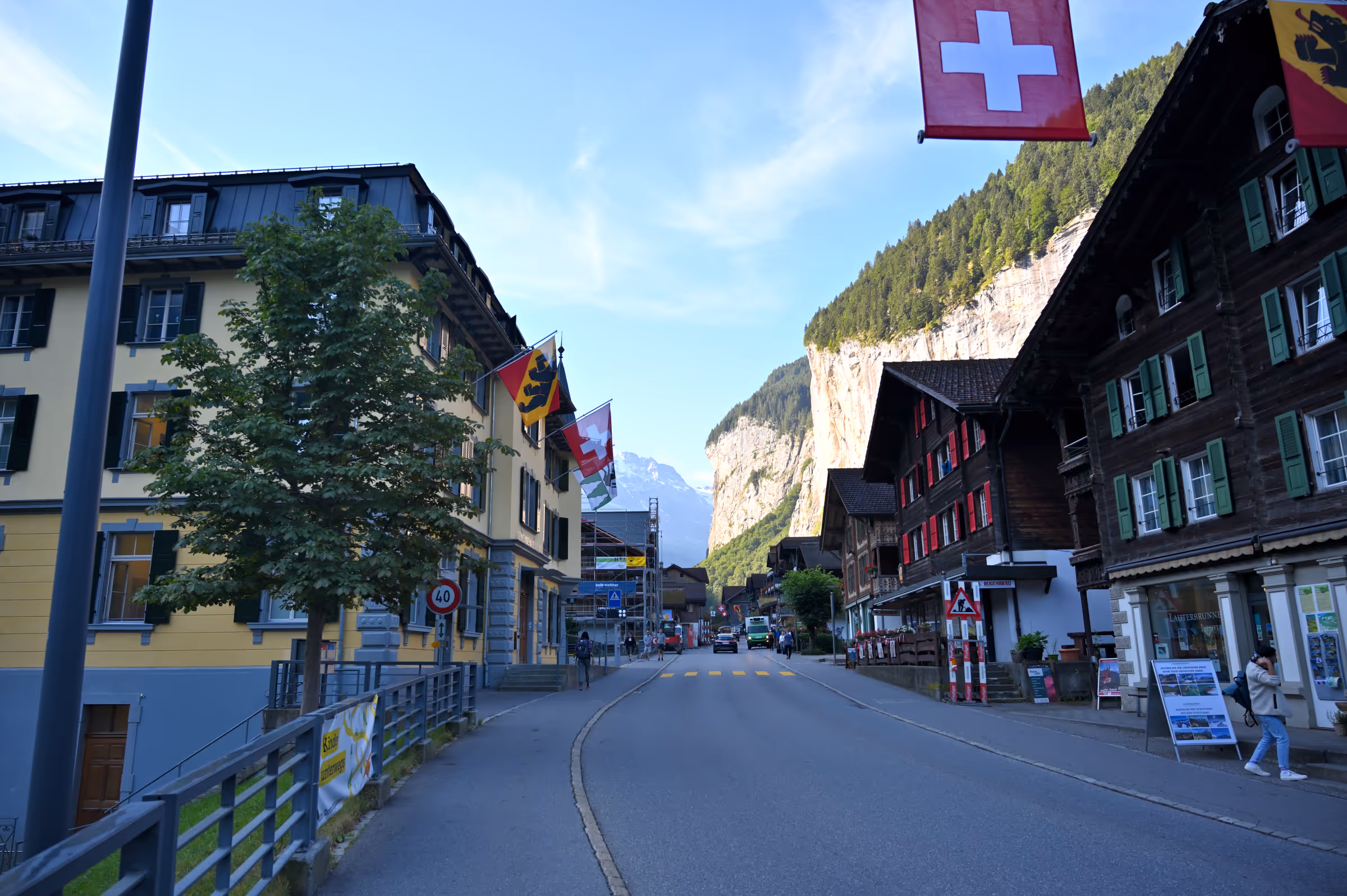 Street view of downtown Lauterbrunnen with alpine buildings and steep valley cliffs in Switzerland.