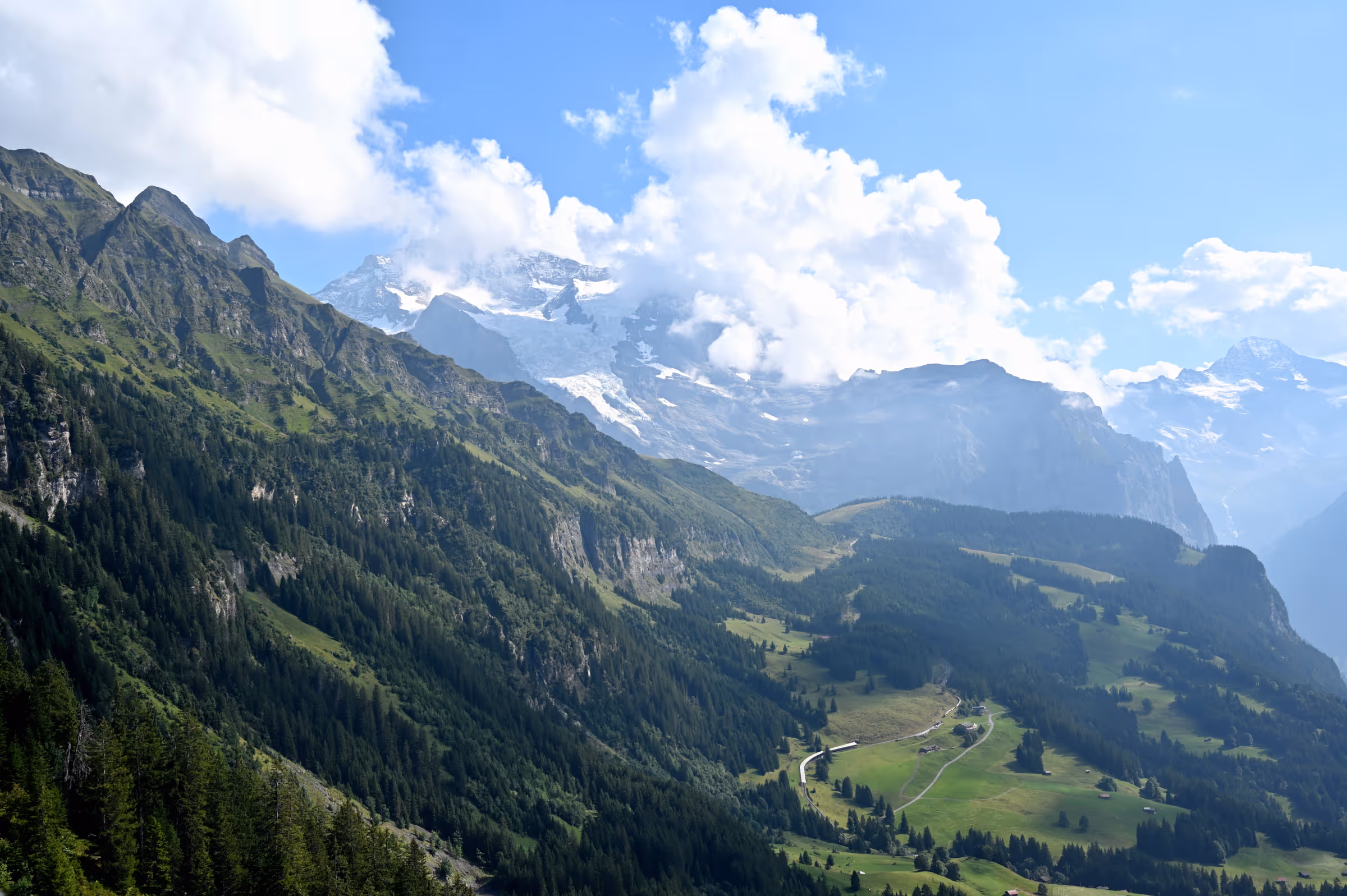 Layered alpine slopes and forested ridges overlooking the Lauterbrunnen Valley in the Swiss Alps.