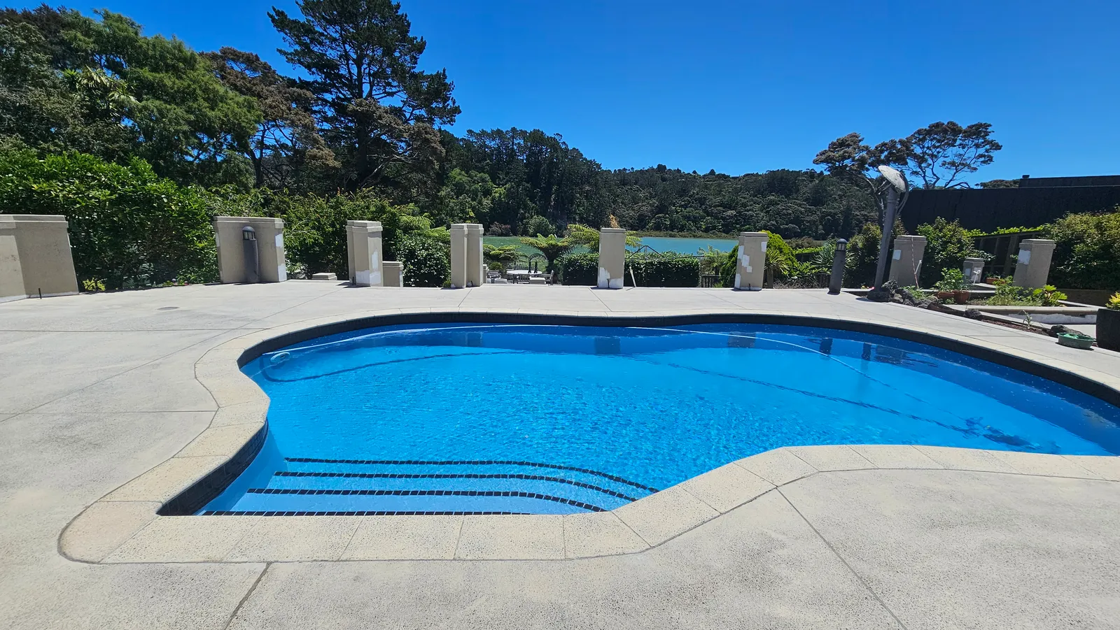 Restored concrete pool surround with natural sealer in Whitford, East Auckland