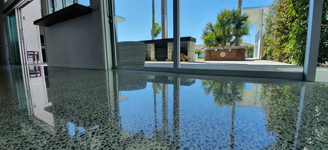 Diamond Shine Concrete high-gloss polished concrete floor in Auckland residential living room with large garden-facing glass doors