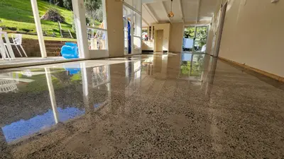Diamond Shine Concrete high-gloss polished pre-1990 concrete floor in an Auckland home with garden and pool views through floor-to-ceiling windows