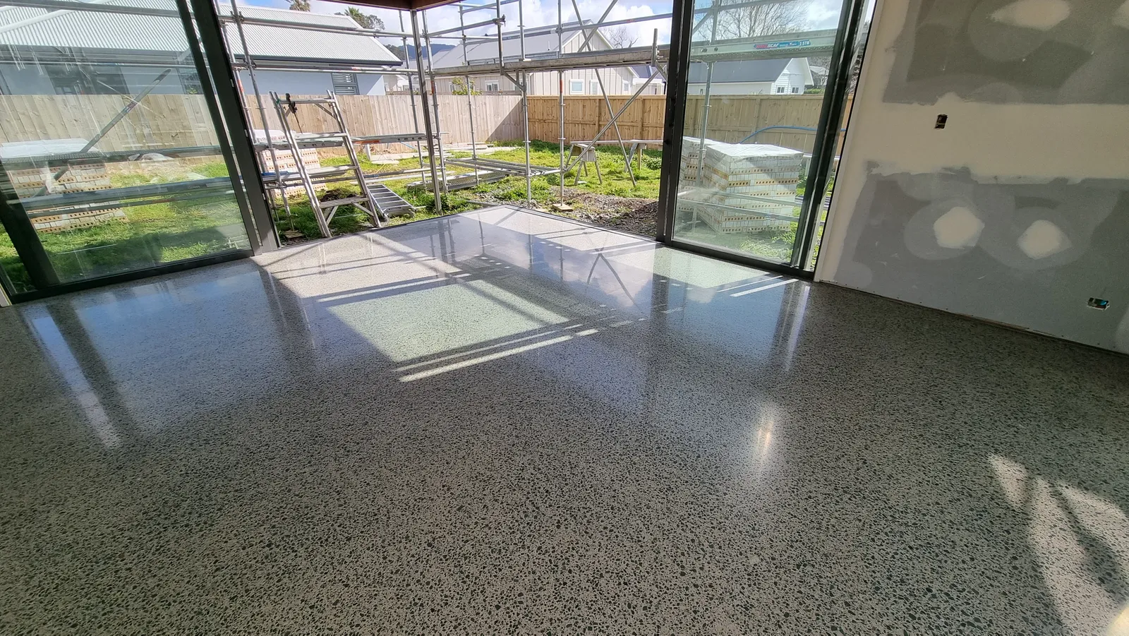 Diamond Shine Concrete semi-gloss medium-grind polished concrete floor in an Auckland new build with bifold glass doors