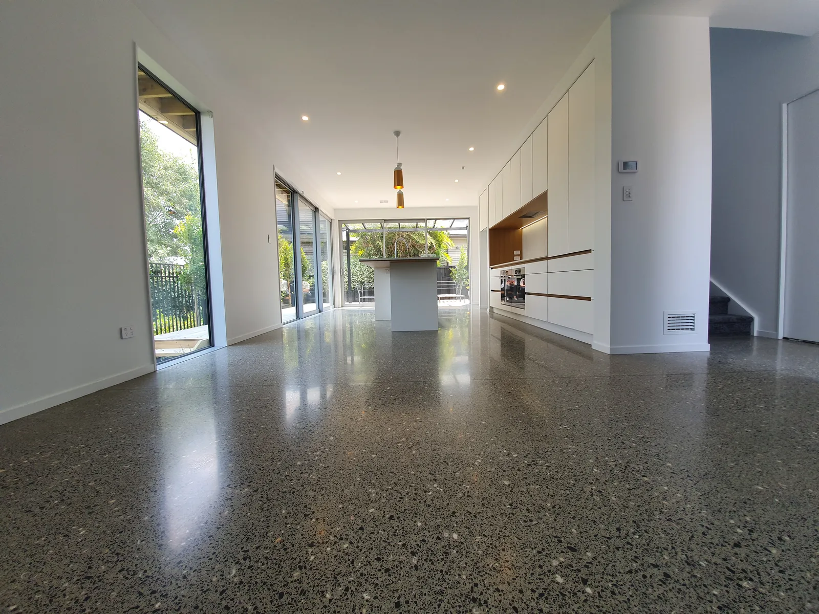 Diamond Shine Concrete decorative polished concrete floor throughout an Auckland open-plan home with natural light