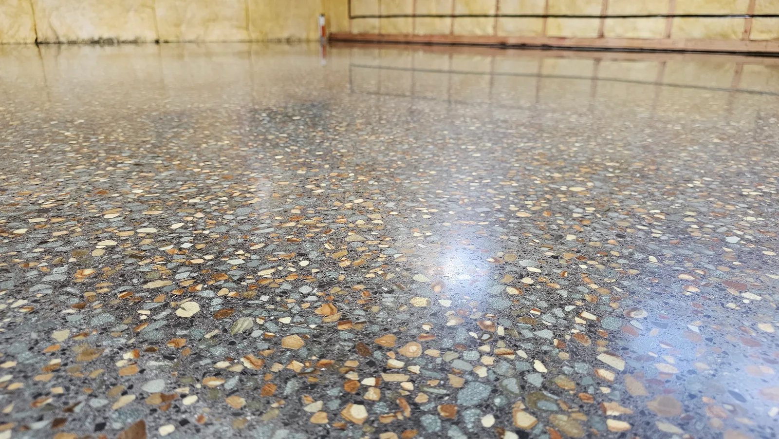Diamond Shine Concrete polished concrete floor close-up showing large exposed aggregate with warm-toned river stones in Auckland