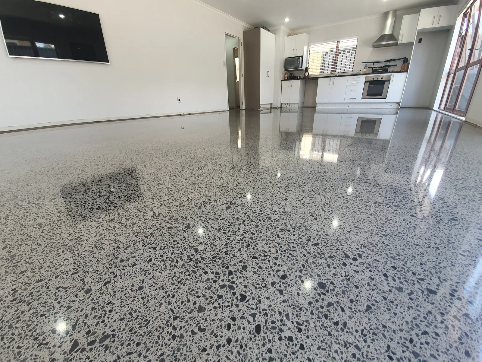 Diamond Shine Concrete high-gloss polished concrete floor in open-plan Auckland kitchen and living room with salt-and-pepper aggregate