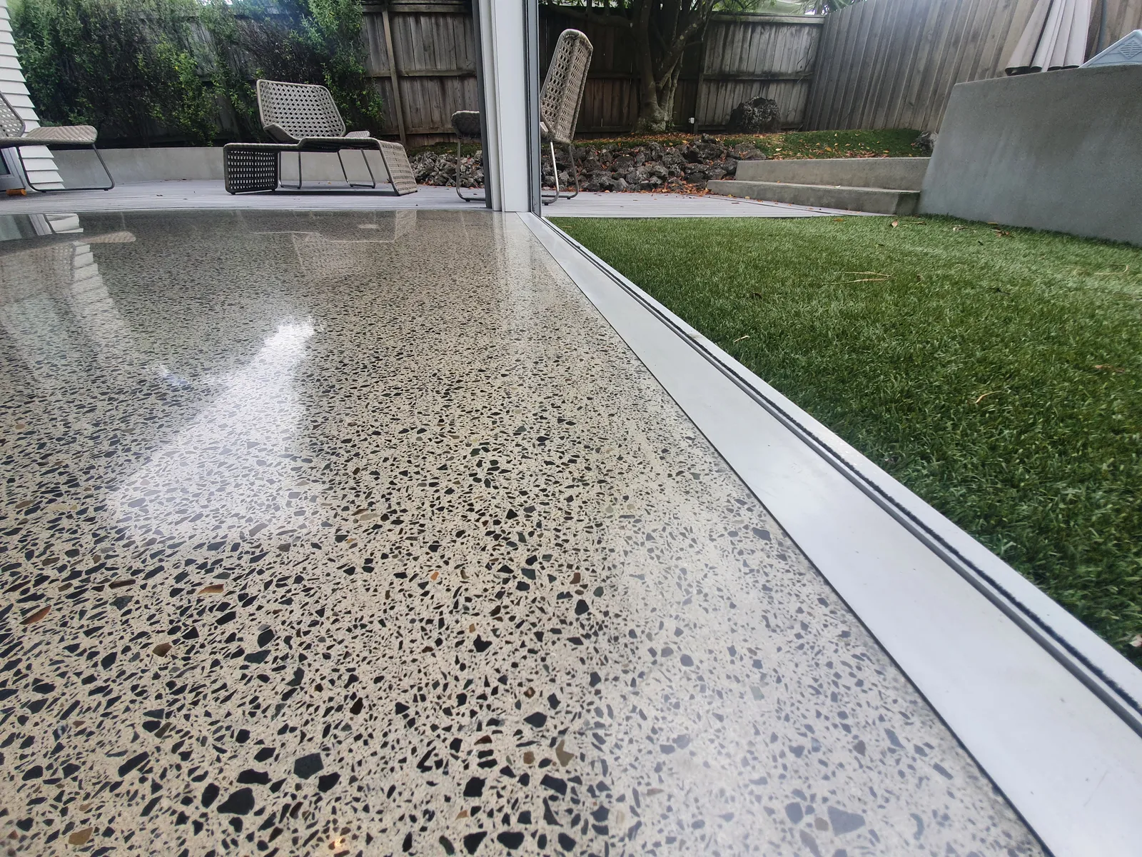 Diamond Shine Concrete high-gloss polished concrete floor detail showing exposed aggregate near sliding doors in Auckland home
