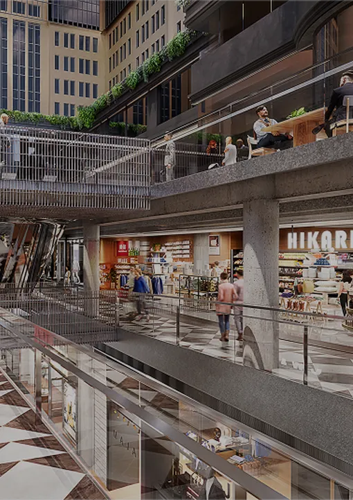 Modern multi-level shopping mall interior with stores, shoppers walking, and people dining on an upper-level balcony.
