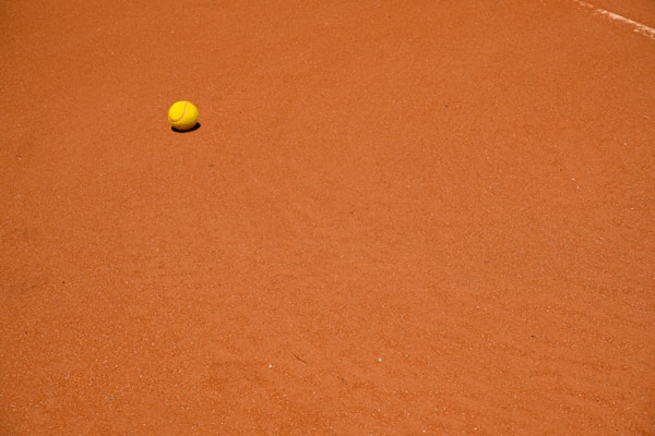 A tennis ball sitting on a clay court