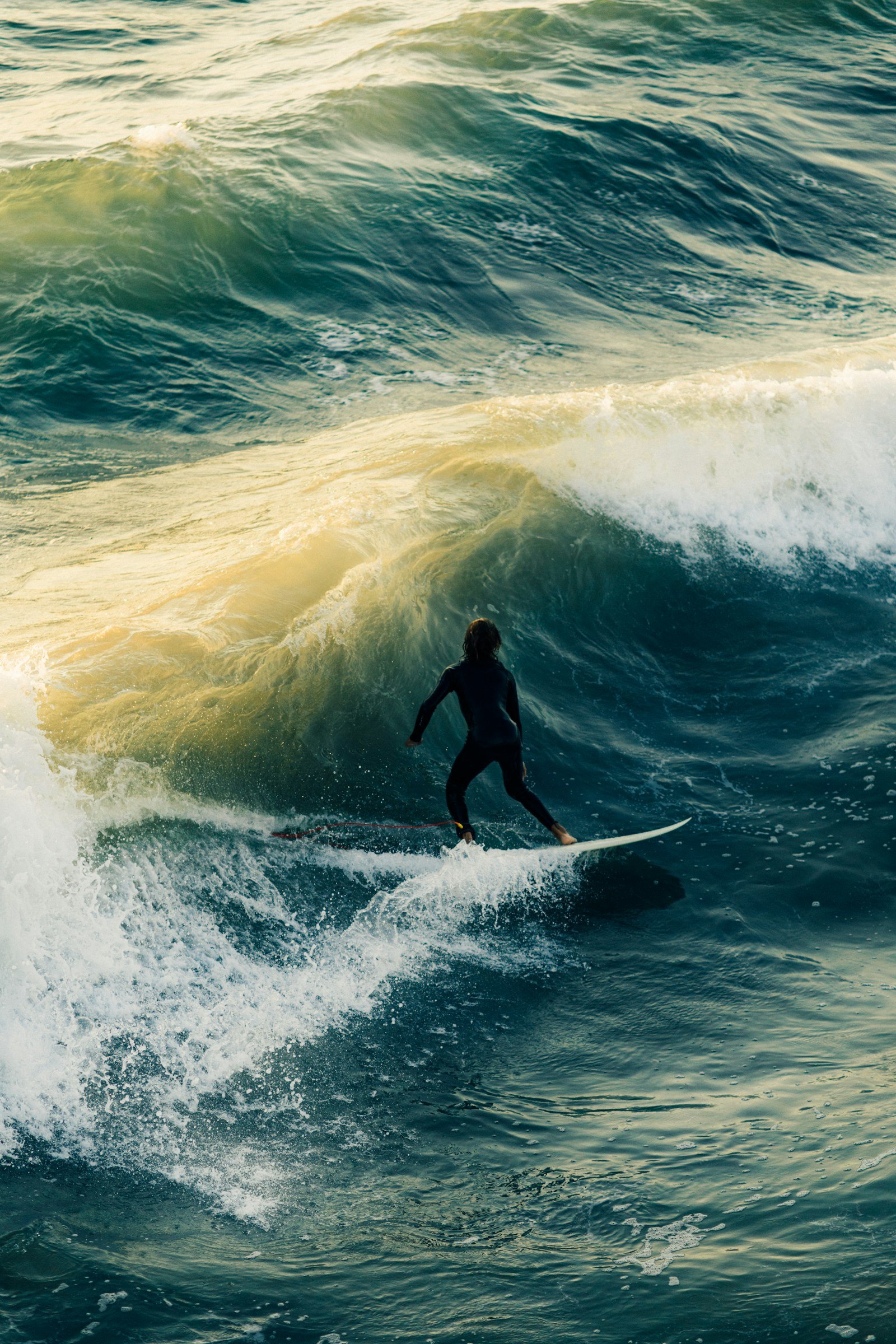 Un surfeur en combinaison prend une vague dans la lumière du soir