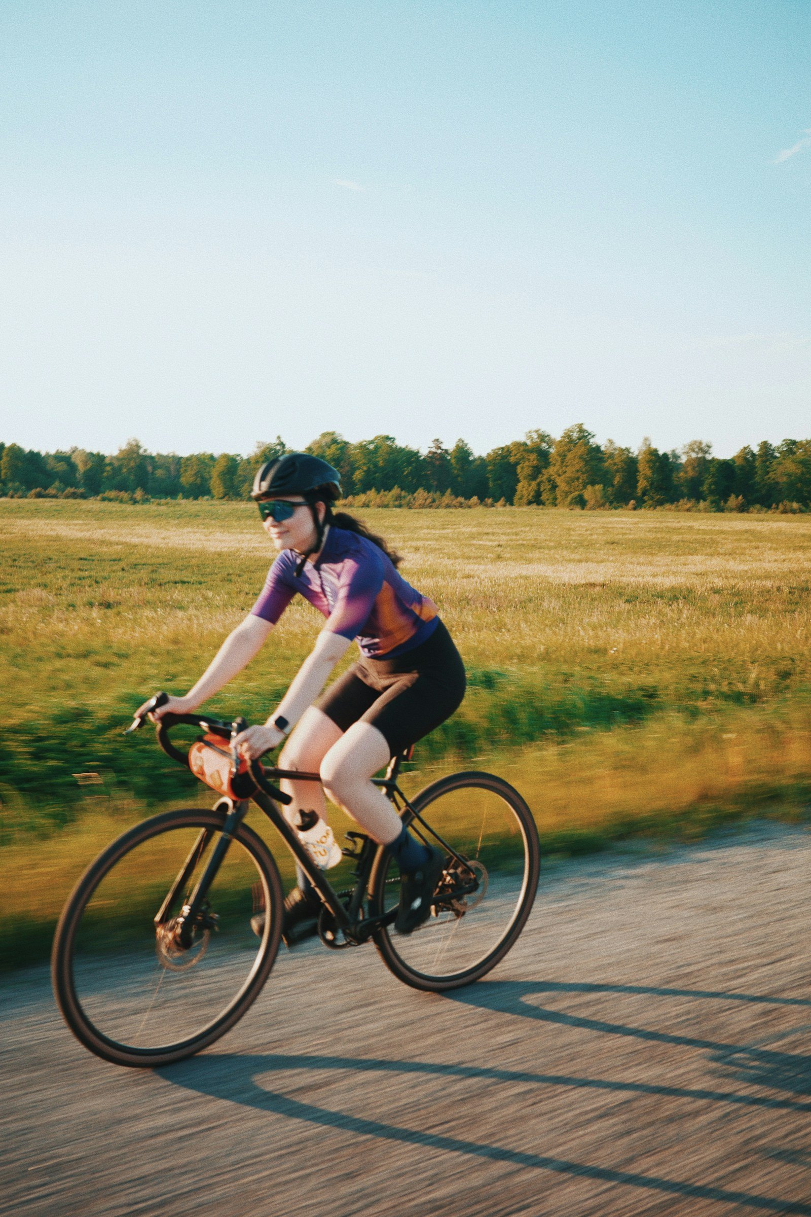 Une cycliste roule sur une route de campagne au soleil rasant