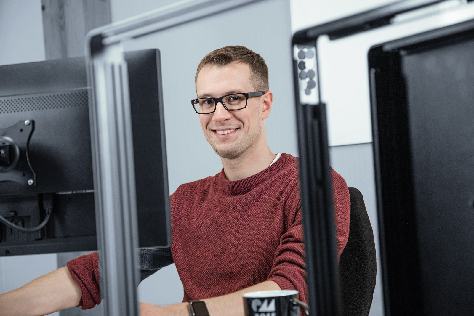 Engineer smiling at his desk between two HMI screens