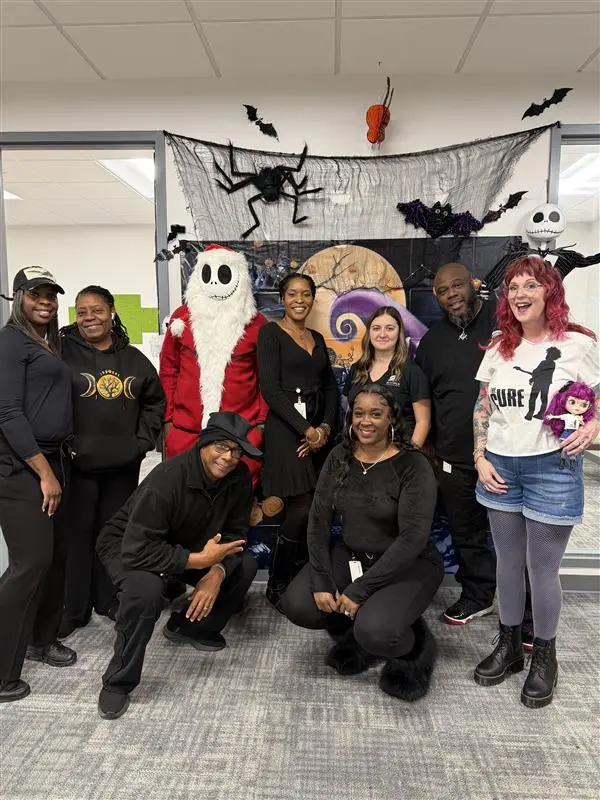 Three women posing for a picture in front of a wall.