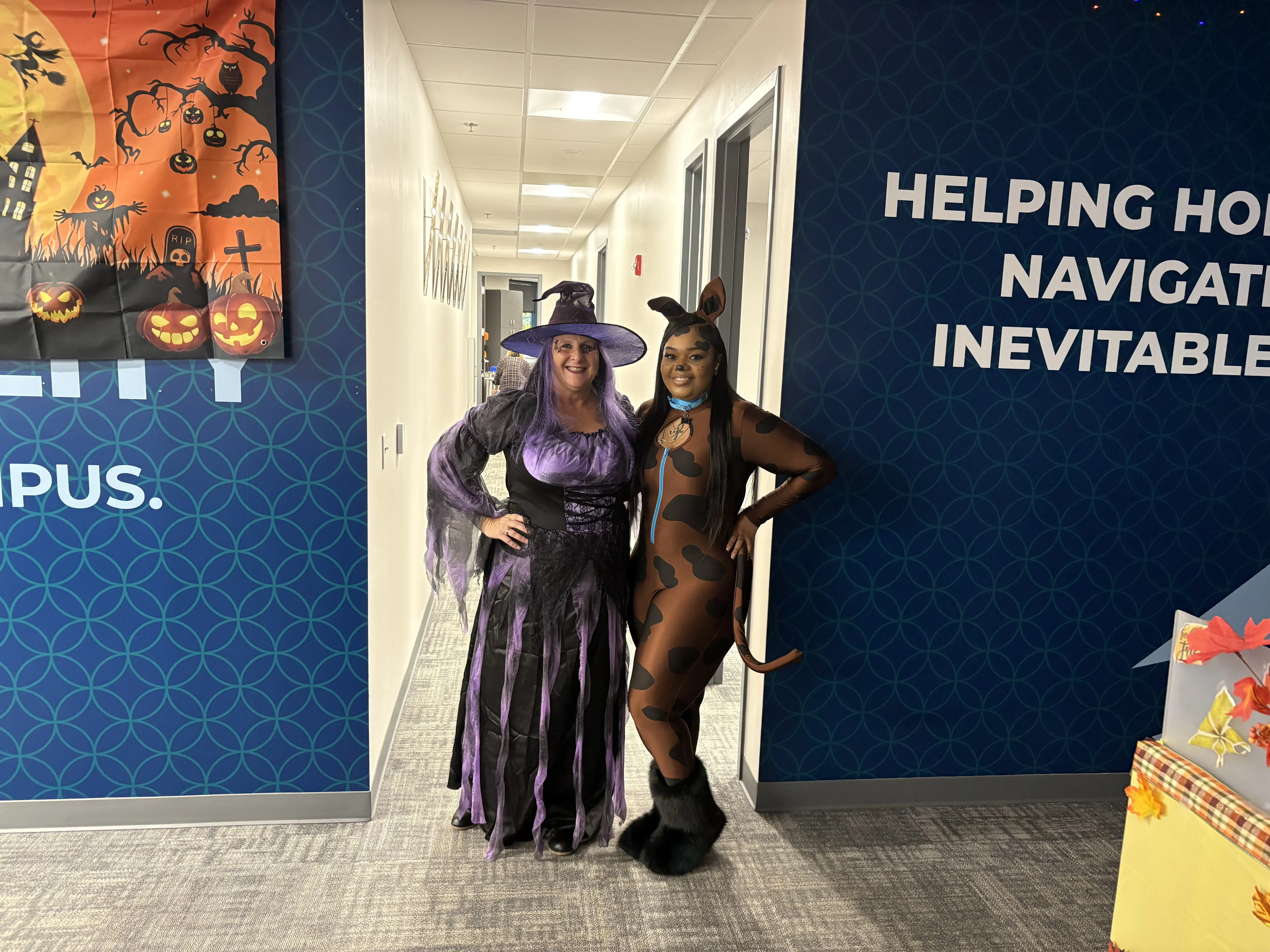 Three women posing for a picture in front of a wall.