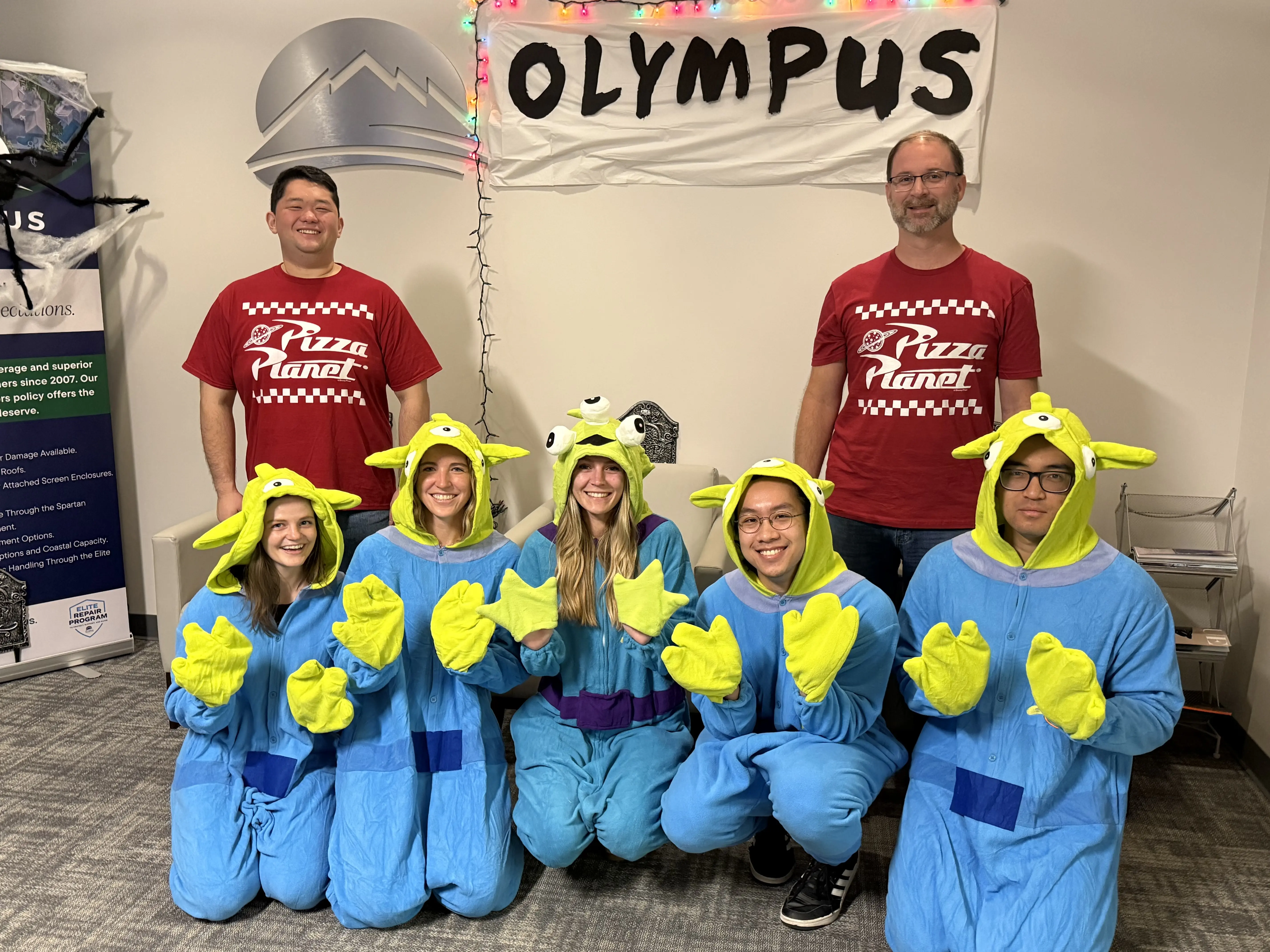 Three women posing for a picture in front of a wall.