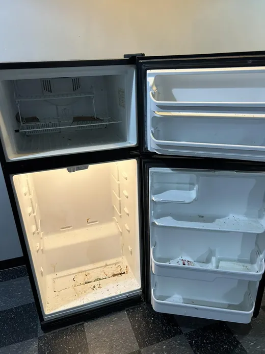 Before a deep cleaning in Miami: crumbs and spills on the fridge shelves