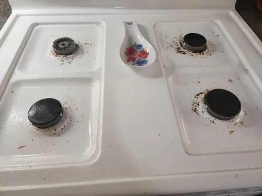 Before a deep cleaning in Miami: crumbs and grease on a white stovetop